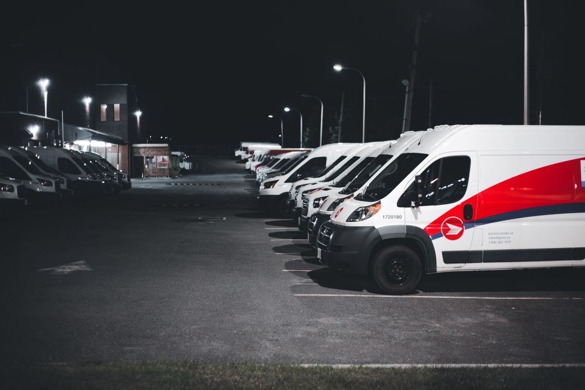 Flota de camionetas de reparto estacionadas de noche, ilustrando el seguro de flotas automotor